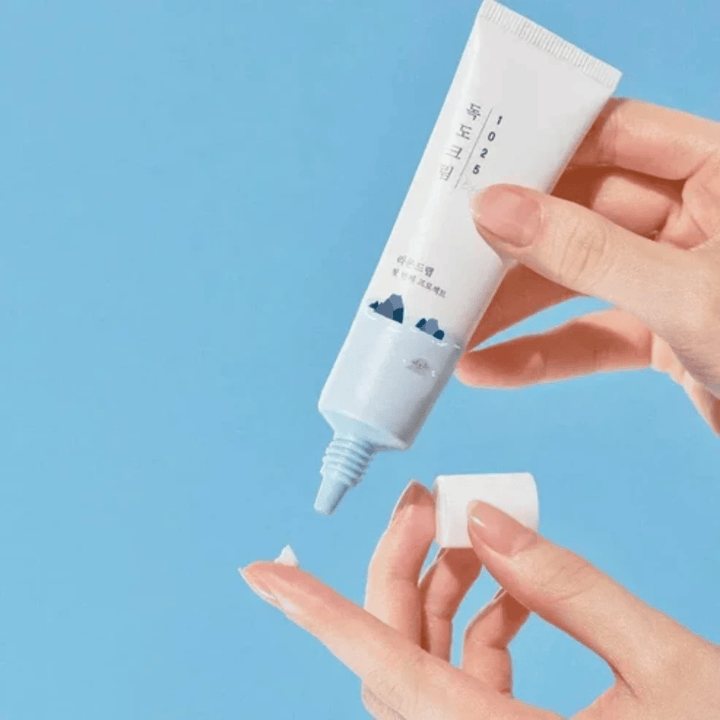 Round Lab 1025 Dokdo Eye Cream tube met lichte crème die op de vingertop wordt aangebracht voor zachte verzorging van de gevoelige huid rond de ogen
