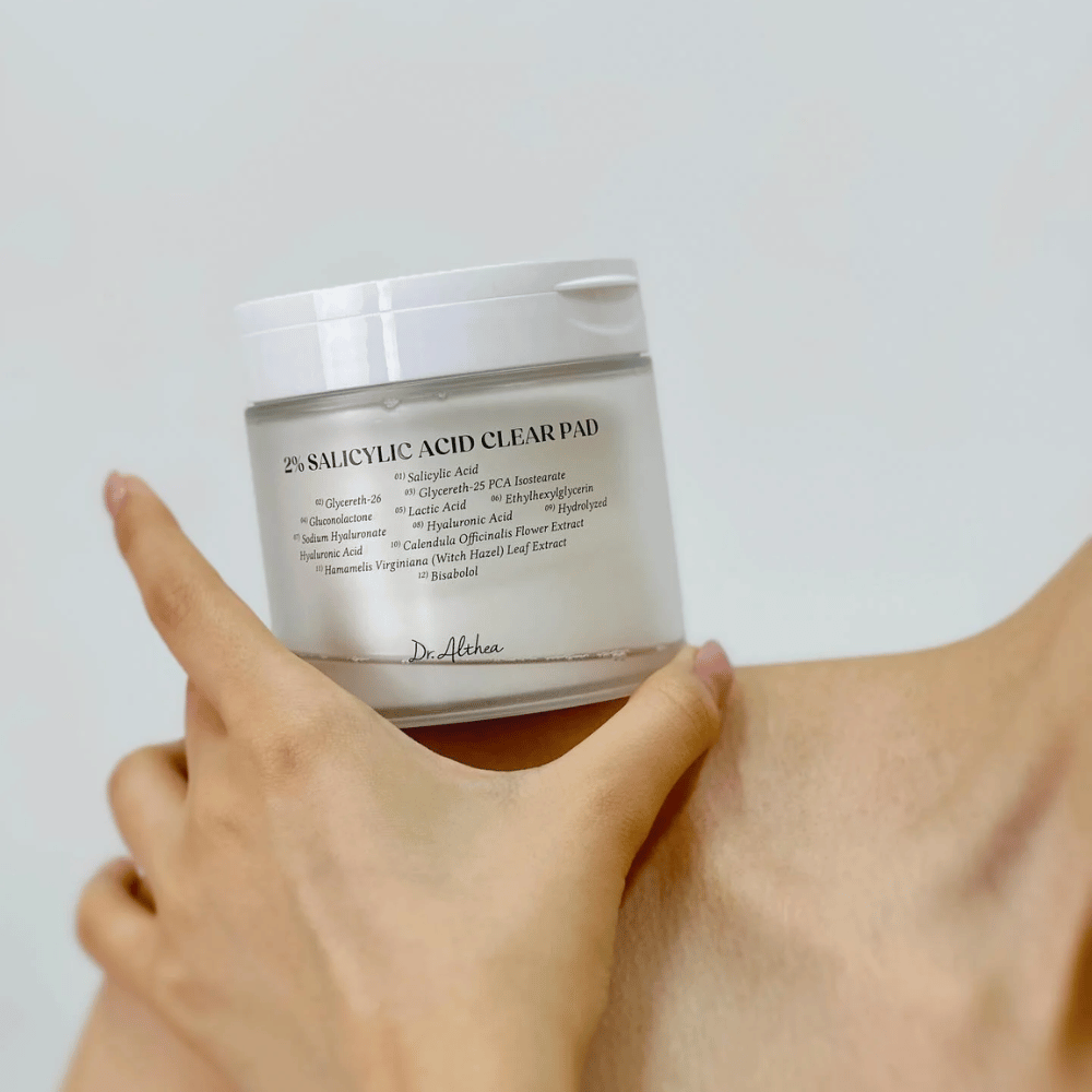 Dr. Althea 2% Salicylic Acid Clear Pad wordt in de hand gehouden. Toner pads met 2% salicylzuur die zacht exfoliëren, de huid kalmeren en de huidstructuur verbeteren.
