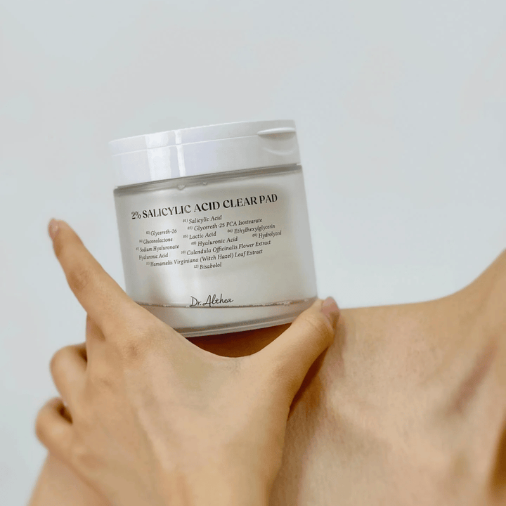 Dr. Althea 2% Salicylic Acid Clear Pad wordt in de hand gehouden. Toner pads met 2% salicylzuur die zacht exfoliëren, de huid kalmeren en de huidstructuur verbeteren.