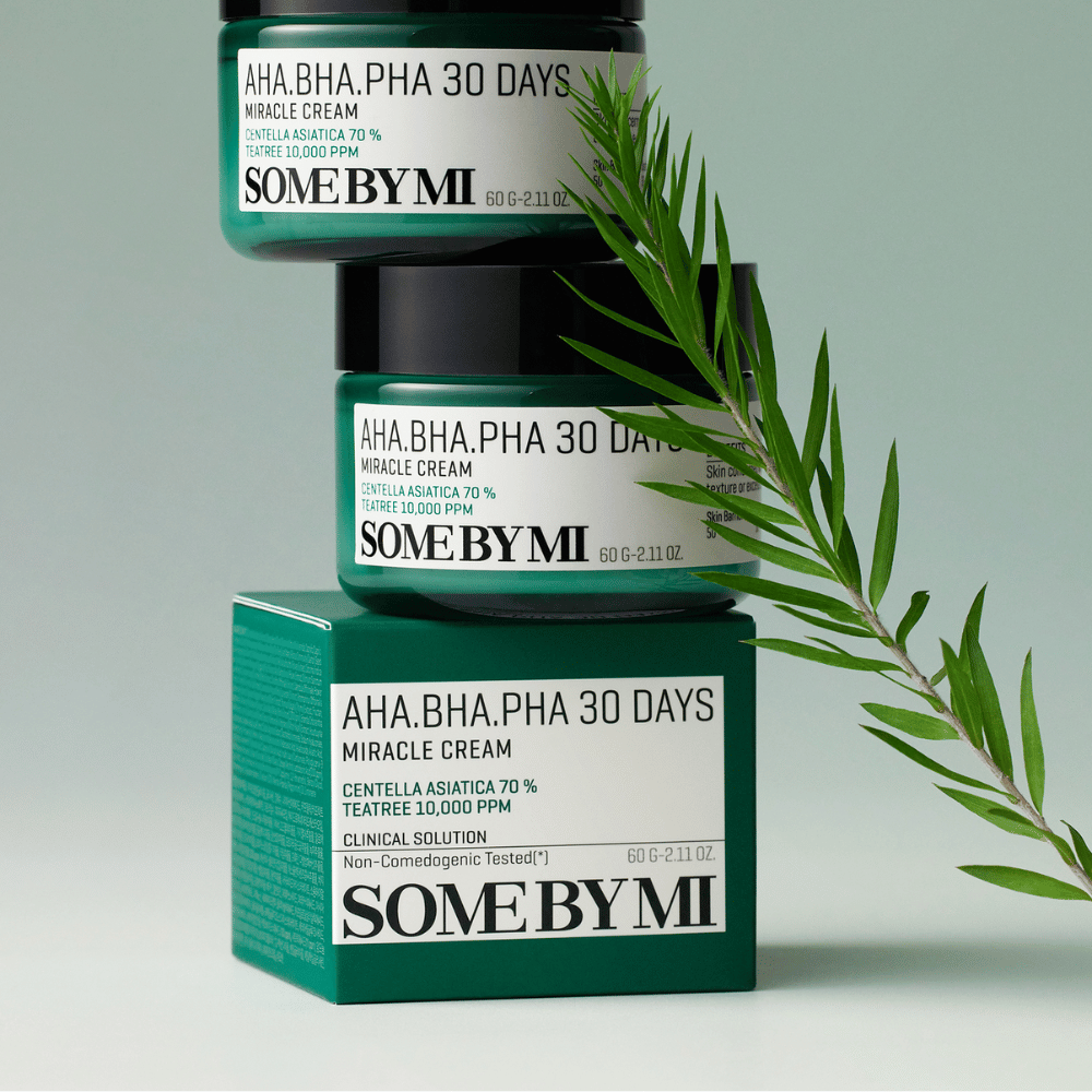 Een afbeelding die twee potten van "SOME BY MI AHA, BHA, PHA 30 Days Miracle Cream" toont, gestapeld op een groen getinte doos. De crème, rijk aan centella asiatica en tea tree-olie, is ontworpen om de huidkwaliteit te verbeteren en probleemhuid te verzachten. Werkt hydraterend en kalmerend.