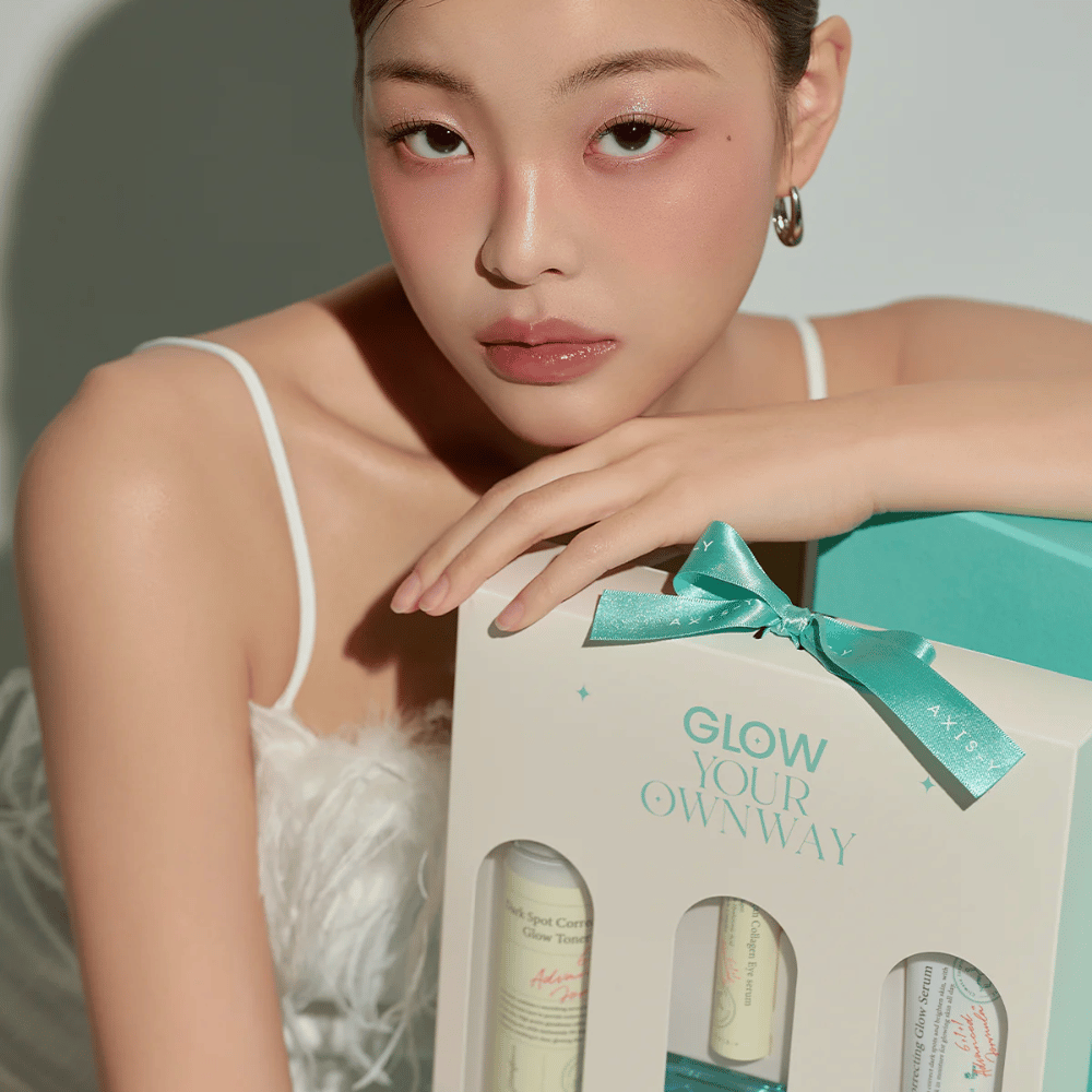Model met elegante make-up houdt de “Glow Your Own Way”-cadeaubox van AXIS-Y vast – een stijlvol Huidverzorgingsset perfect als cadeau voor jezelf of iemand van wie je houdt.