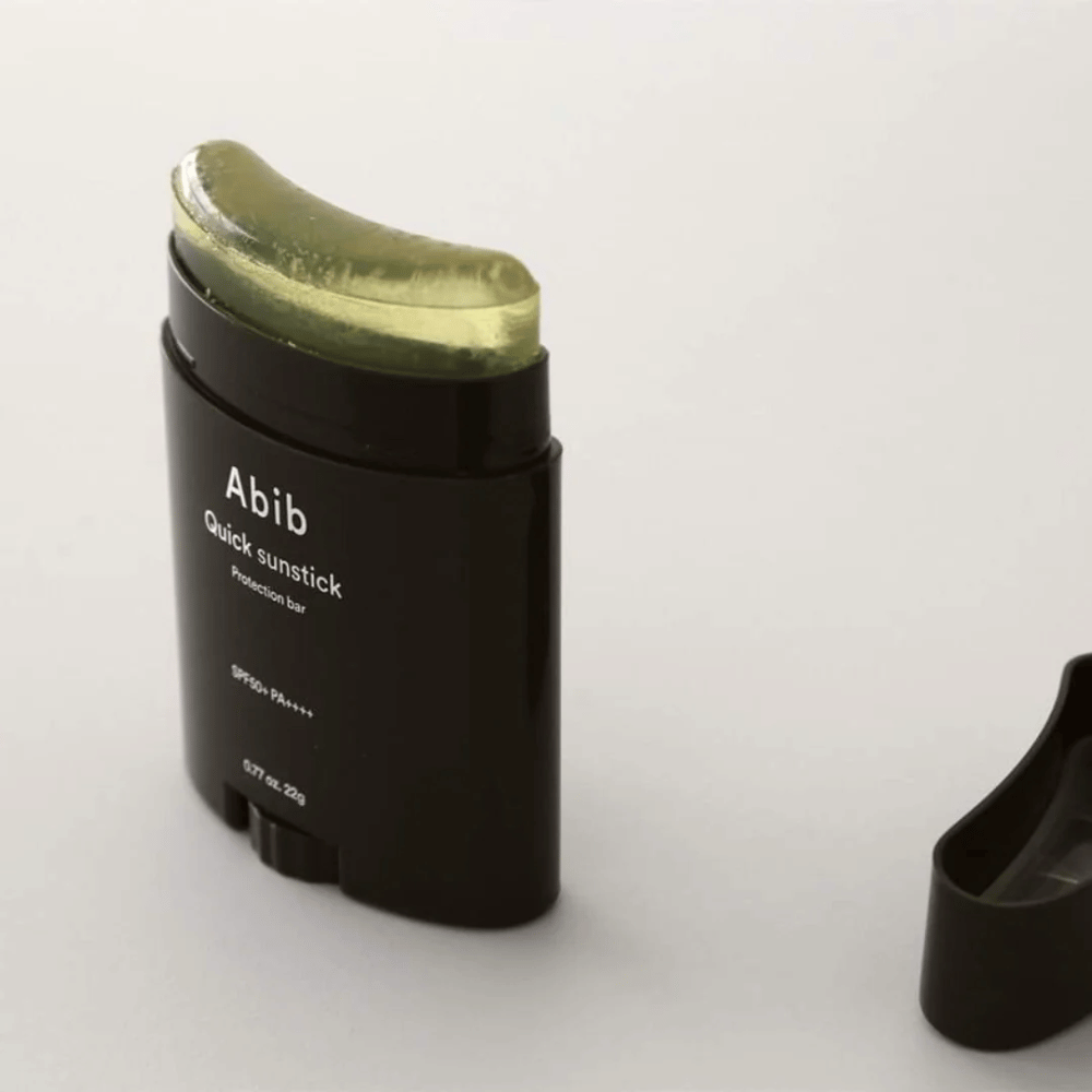 Een zwarte buis met een groene dop, bevat Quick Sunstick Protection Bar SPF50+ PA++++ 22g van Abib voor zonnebescherming.