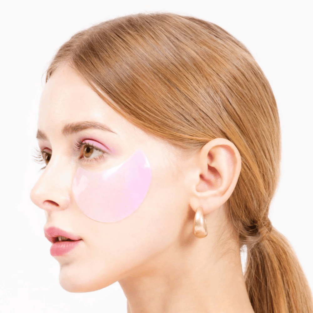 Model draagt een roze hydrogel oogpatch onder het oog, hydraterend en huidverjongend.