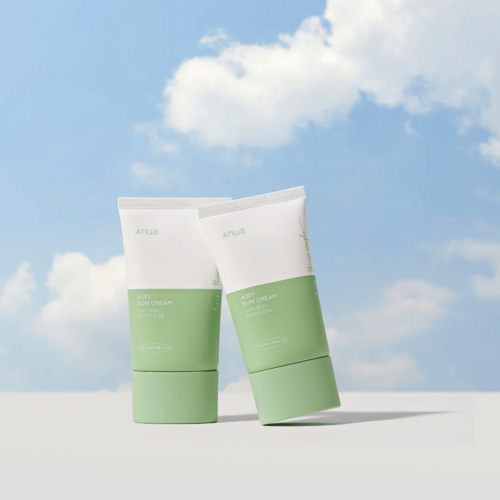Twee tubes van Anua Airy Sun Cream tegen een lucht met witte wolken.