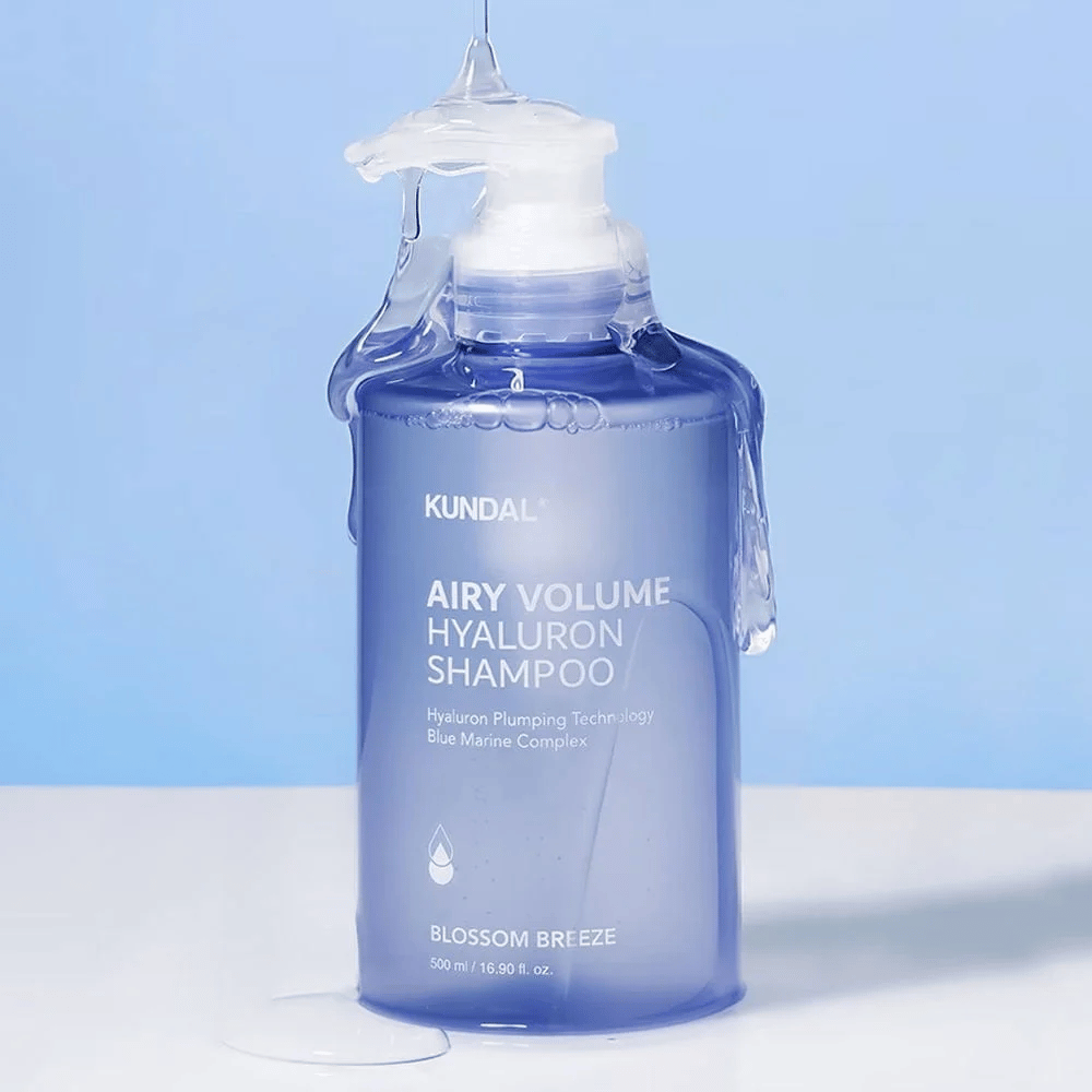 KUNDAL Airy Volume Hyaluron Shampoo Blossom Breeze in blauwe pompflacon, met hyaluron en Blue Marine Complex, gefotografeerd met stromend water.