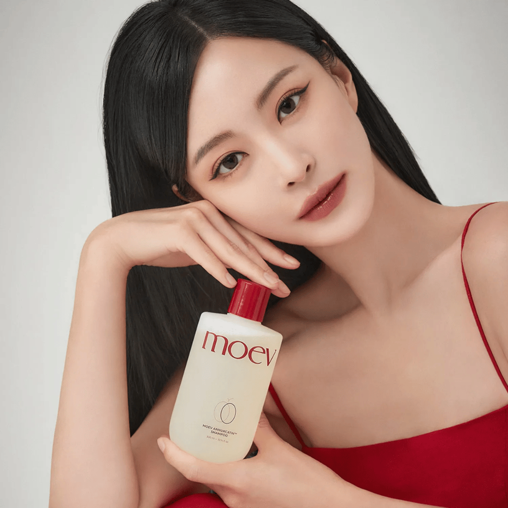 Vrouw met lang, glanzend haar houdt MOEV Annurcatin Shampoo vast – een Koreaanse shampoo die het haar hydrateert, versterkt en beschermt met natuurlijke ingrediënten.