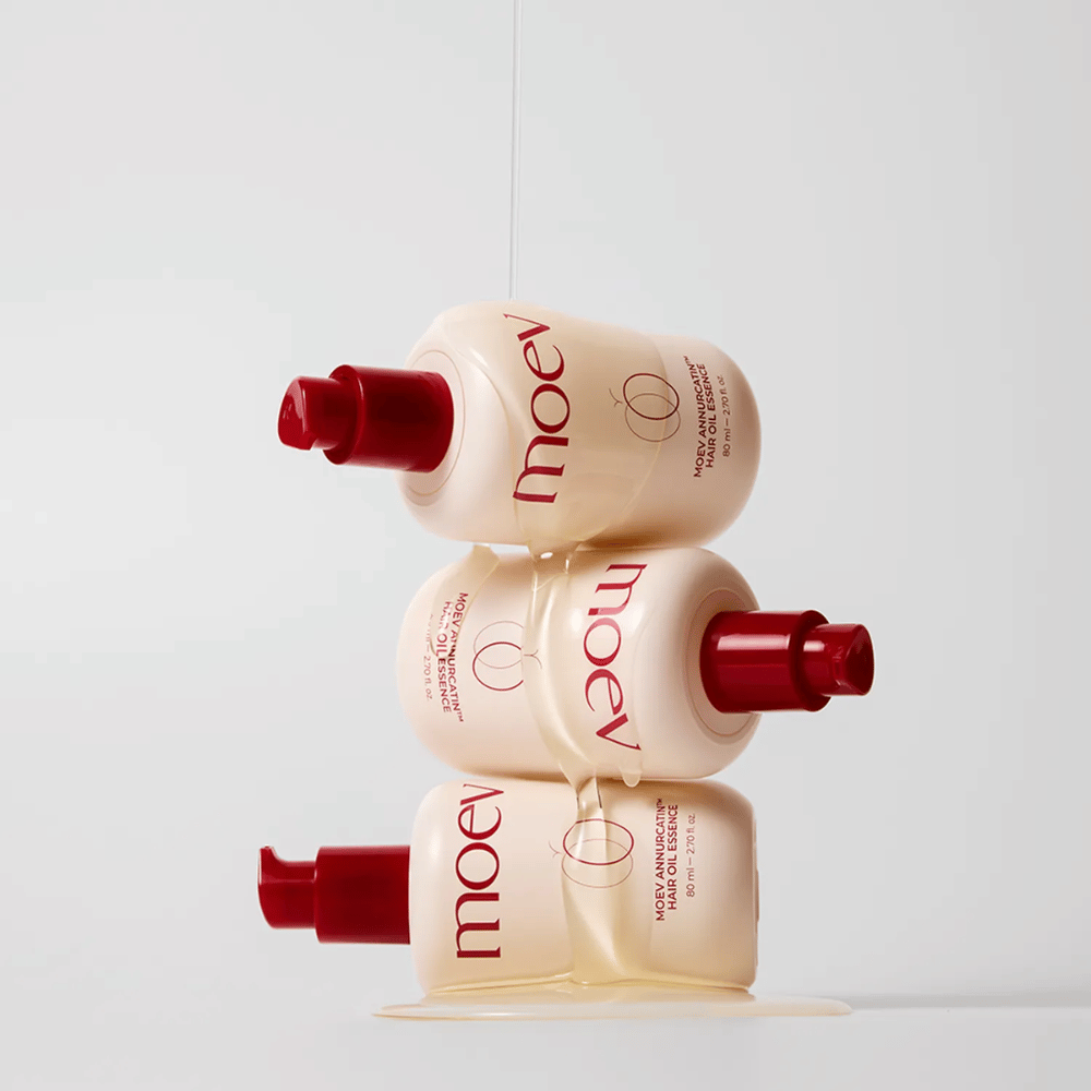 Drie flessen MOEV Annurcatin Hair Oil Essence gestapeld – voedende haarolie met Annurca-appel en biotine die versterkt, beschermt en het haar glans en elasticiteit geeft.