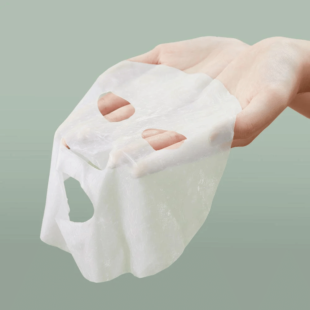 Een hand van een persoon die Anua Heartleaf 77% Soothing Sheet Mask vasthoudt.