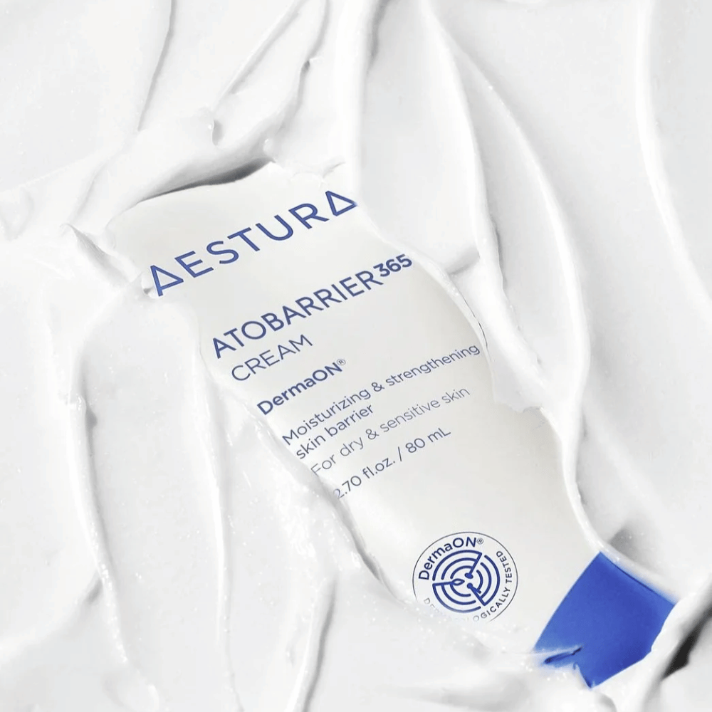 Aestura Atobarrier 365 Cream is perfect voor droge en gevoelige huid. Met DermaON™ technologie hydrateert en versterkt deze crème de huidbarrière. Het product wordt hier getoond in een tube van 80 ml, gedeeltelijk bedekt door zijn eigen romige textuur, wat de rijke, hydraterende eigenschappen benadrukt.