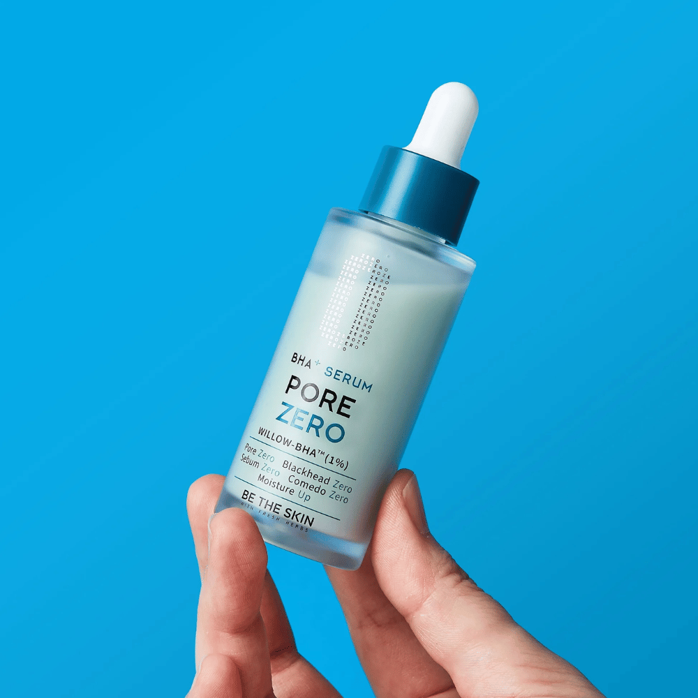 Be The Skin BHA+ Pore Zero Serum wordt in de hand gehouden tegen een blauwe achtergrond