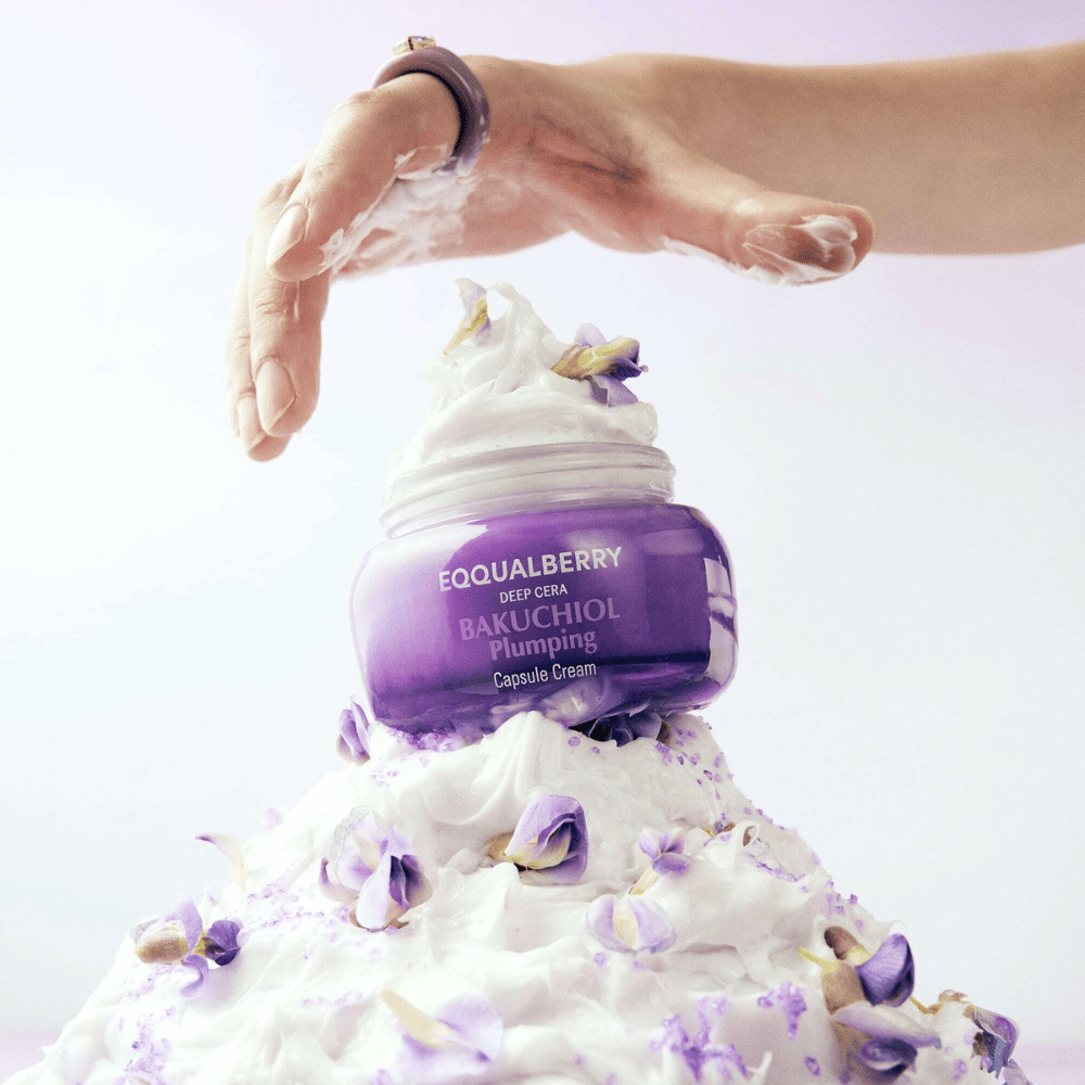 EQQUALBERRY Bakuchiol Plumping Capsule Cream geplaatst bovenop een hoop opgeklopte crème met bloemblaadjes – symboliseert vocht en verzorging.
