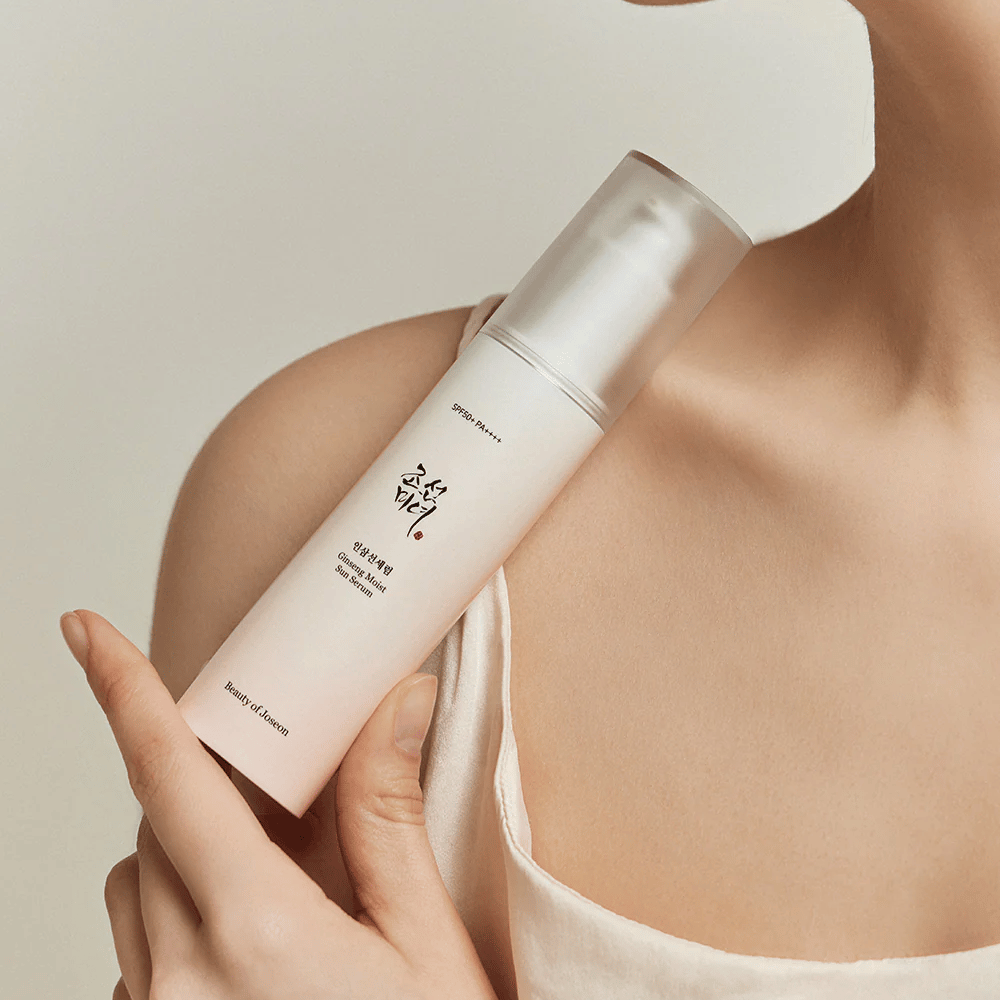 Een vrouw die een fles Beauty of Joseon's Ginseng Moist Sun Serum SPF 50+ PA++++ vasthoudt, die SPF 50+ PA++++ bescherming en huidverzorgingsvoordelen biedt.