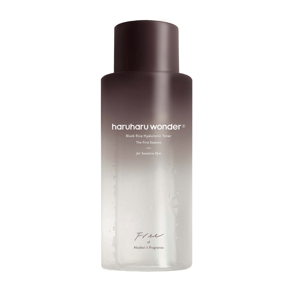 Een fles van haruharu wonder Black Rice Hyaluronic Toner The First Essence, met donkerbruin tot transparant verloop en de tekst "Vrij van Alcohol & Geur", tegen een witte achtergrond.