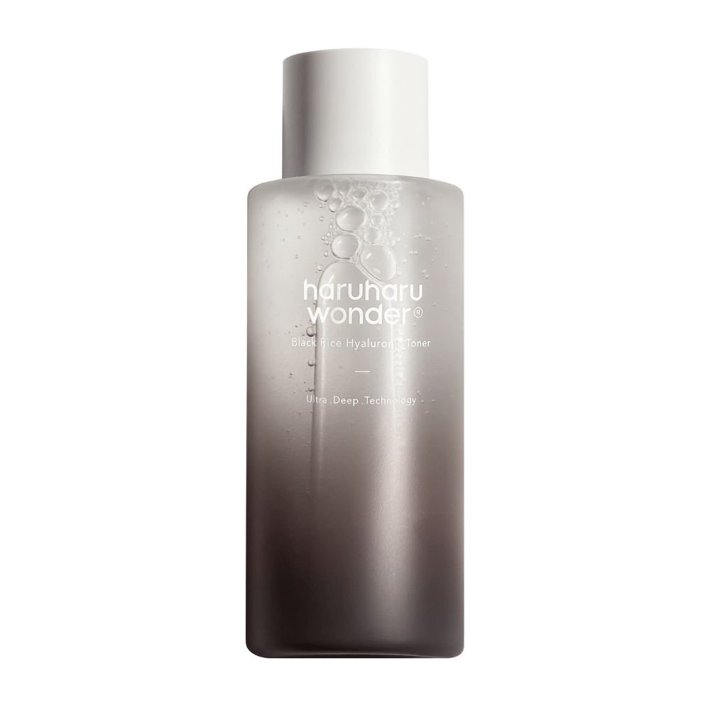 Een fles van haruharu wonder Black Rice Hyaluronic Toner met een grijs tot wit kleurverloop en waterdruppels op het oppervlak, tegen een witte achtergrond.