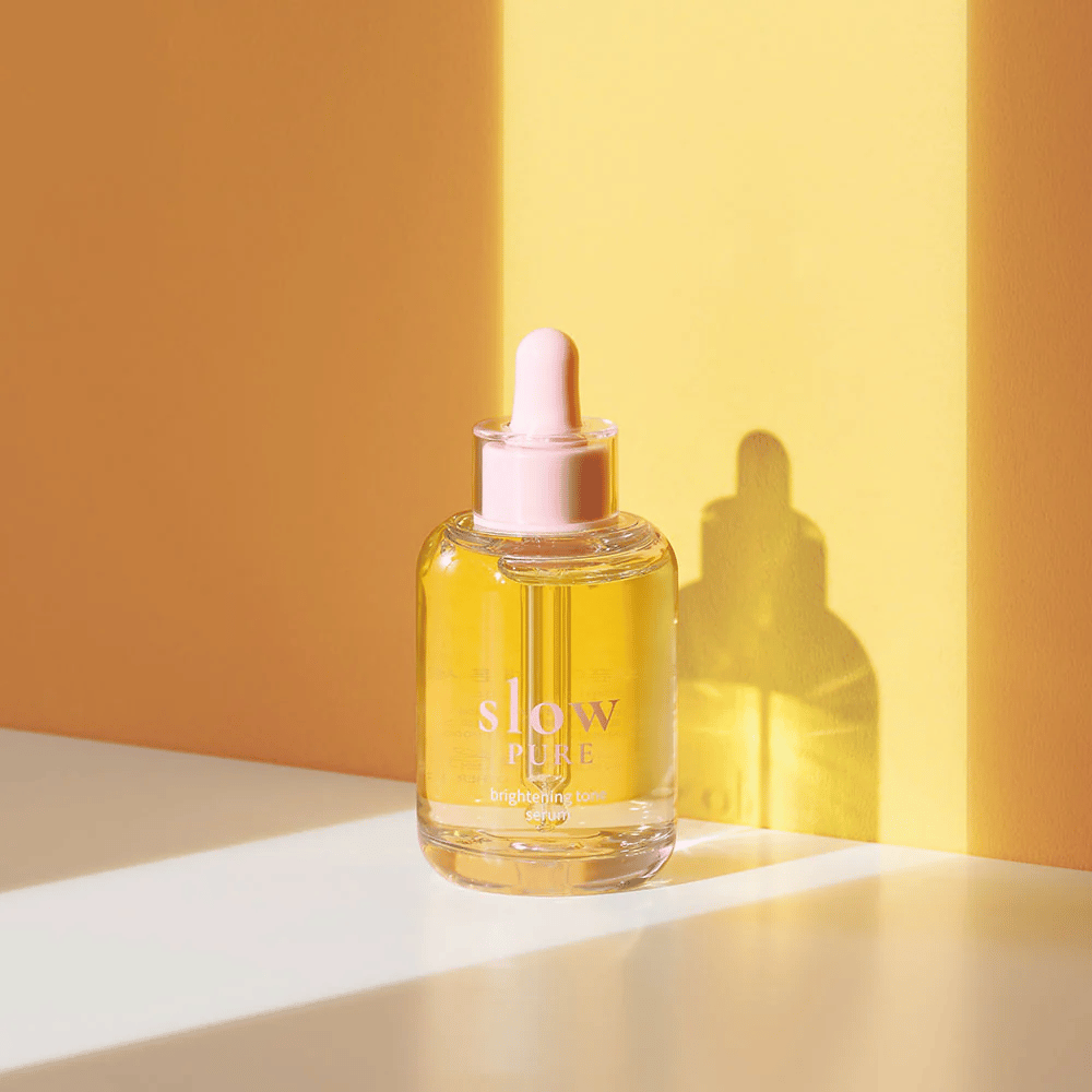Slow Pure Brightening Tone Serum in zonnig geel licht, symboliseert glans en energie voor de huid.