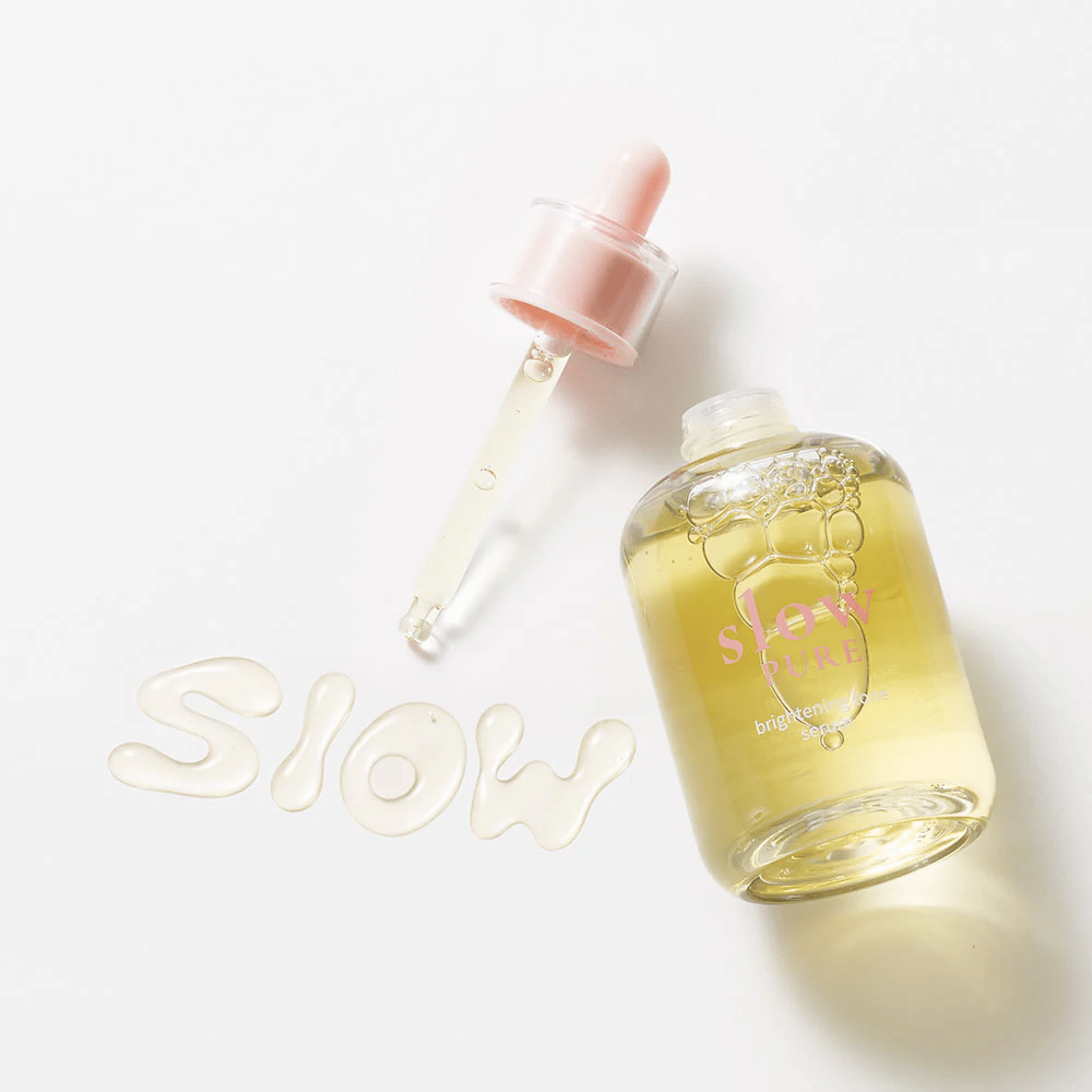 Slow Pure Brightening Tone Serum met open pipet, tekst geschreven in serum op het oppervlak: "Slow".