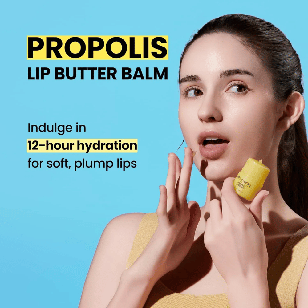 Een vrouw brengt CNP Laboratory Propolis Lip Butter Balm aan, afgebeeld tegen een blauwe achtergrond. Het product belooft 12 uur hydratatie voor zachte en volle lippen, wat wordt getoond met een gele tube die ze in haar hand houdt.