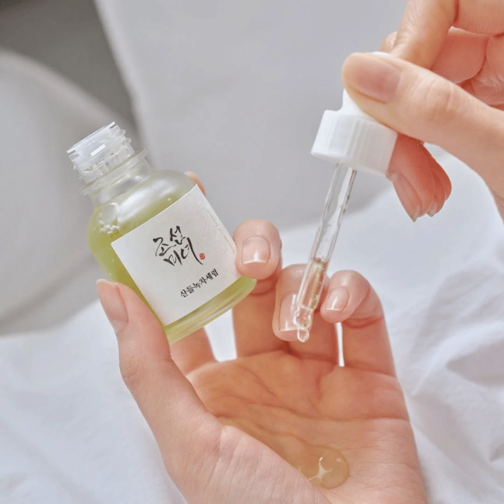 Hand druppelt Beauty of Joseon Calming Serum Green Tea + Panthenol op de huid – kalmerend Koreaans serum voor gevoelige huid.