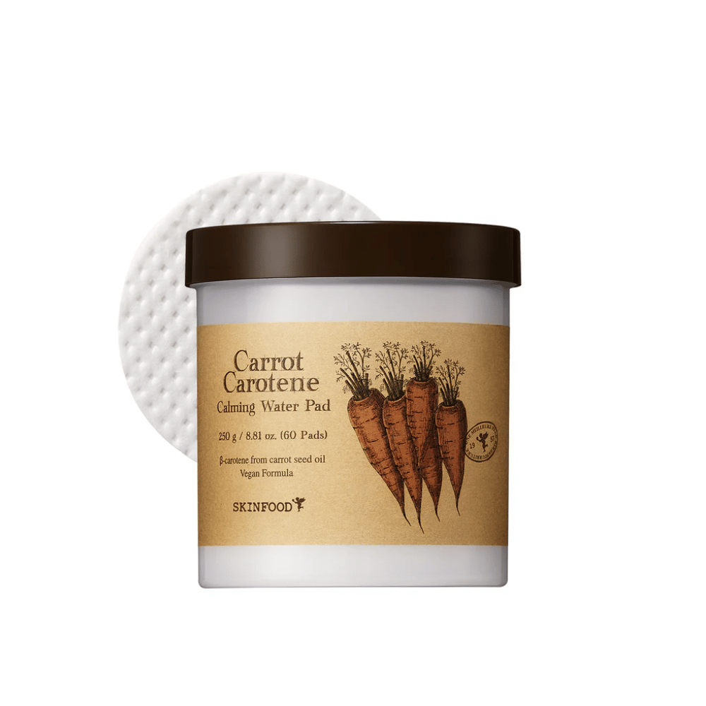 Een pot "Carrot Carotene Calming Water Pad" van SKINFOOD. De pot bevat 60 pads en is gemarkeerd met een afbeelding van wortelen. Het product, dat is gebaseerd op wortelzaadolie, is veganistisch en ontworpen om de huid te kalmeren.