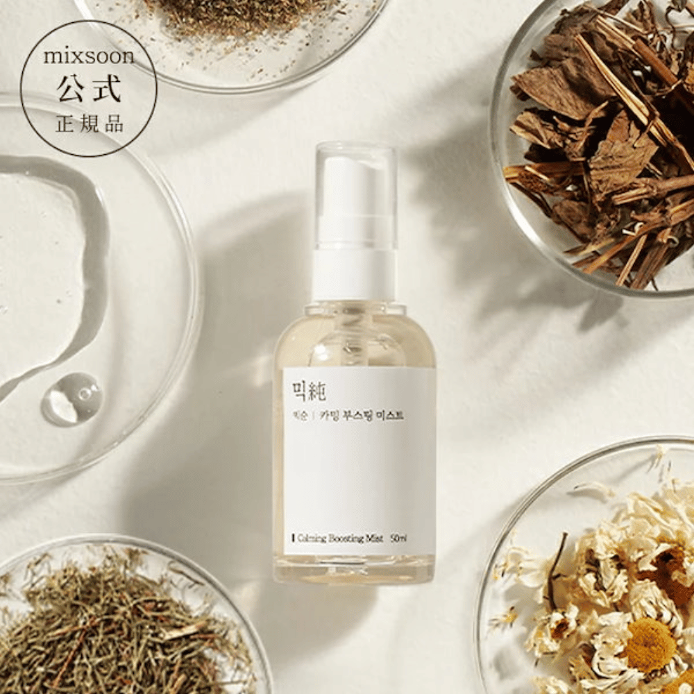 Een doorzichtige sprayfles met het etiket 'Calming Boosting Mist' van Mixsoon, omgeven door gedroogde kruiden en bloemen op witte schalen tegen een beige achtergrond, wat de natuurlijke ingrediënten van de producten benadrukt.