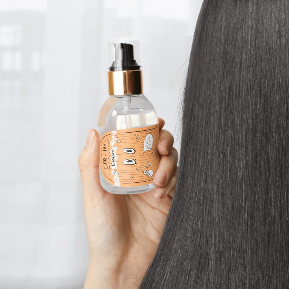 Persoon houdt CER-100 Hair Essence naast lang, glanzend haar om zachtheid en verzorging te tonen.