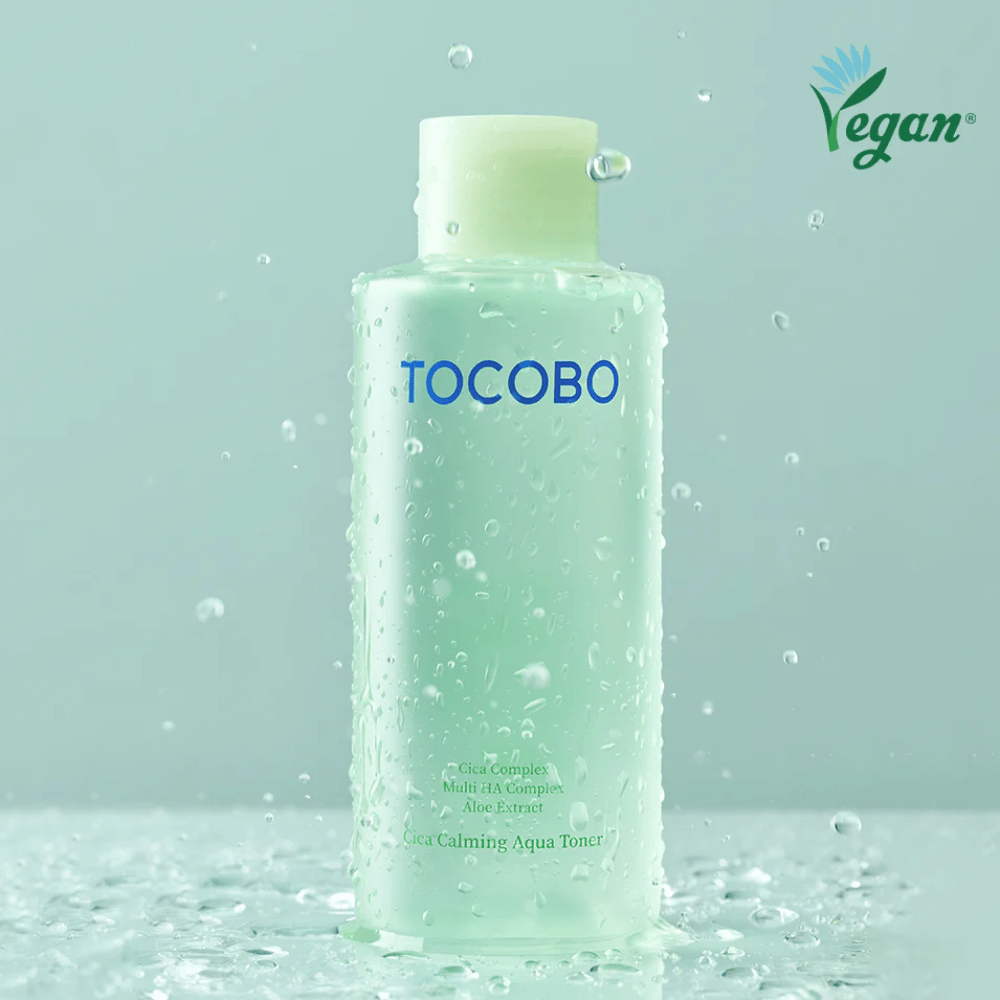 Productafbeelding van TOCOBO Cica Calming Aqua Toner omringd door waterdruppels die de hydraterende en kalmerende eigenschappen van de toner voor de gevoelige huid benadrukken.
