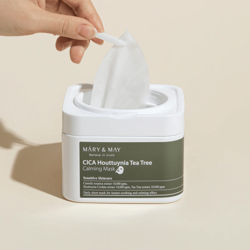 Hand die een sheetmasker uit een Mary & May Cica Houttuynia Tea Tree Calming Mask-pot haalt – kalmerend gezichtsmasker voor gevoelige huid met Cica en Tea Tree-extract.