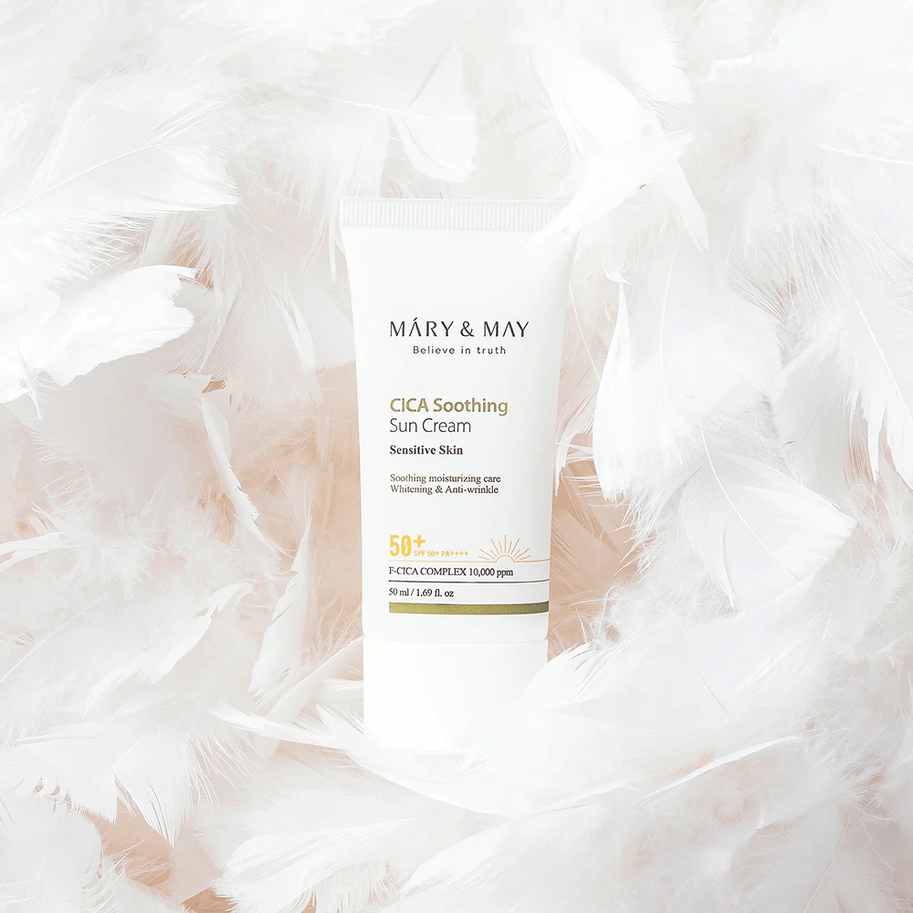Mary&May CICA Soothing Sun Cream omringd door zachte witte veren. De afbeelding brengt een gevoel van zachtheid, comfort en een lichte formule over, afgestemd op de gevoelige huid.