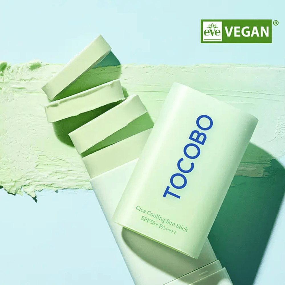 Tocobo Cica Cooling Sun Stick SPF50+ PA++++ in lichtgroene verpakking met vegan keurmerk (EVE VEGAN), liggend op een laag van groene zonstick.