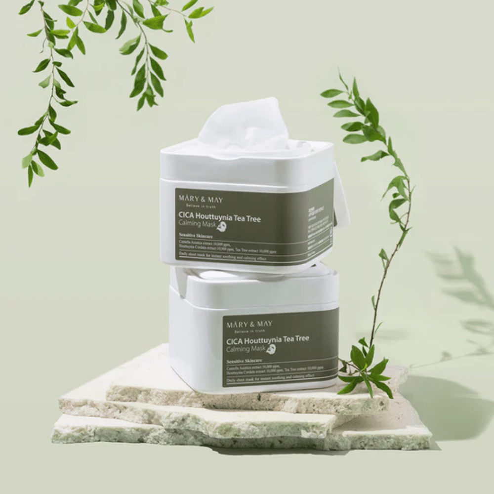 Twee potten Mary & May Cica Houttuynia Tea Tree Calming Mask geplaatst op natuursteen met groene plantdetails – kalmerende sheetmaskers voor gevoelige huid.
