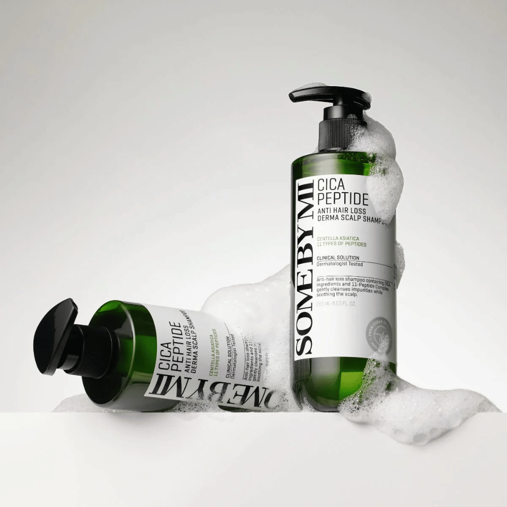 Twee flessen van SOME BY MI Cica Peptide Anti Hair Loss Derma Scalp Shampoo bedekt met schuim, staande en liggende tegen een witte achtergrond.