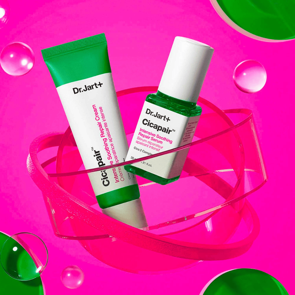 Dr.Jart+ Cicapair Intensive Soothing Repair Cream en Serum in groene verpakkingen, die op een roze cirkelvormige basis staan. De producten zijn ontwikkeld om geïrriteerde huid te kalmeren en te herstellen.