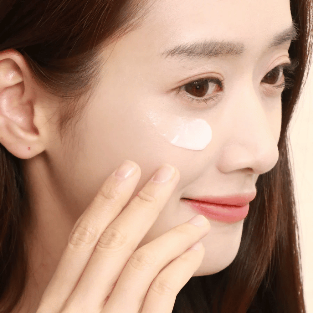 Vrouw brengt oogcrème aan onder het oog met de vingertoppen - close-up die laat zien hoe het product voorzichtig in de huid wordt gemasseerd voor hydratatie en verzorging.