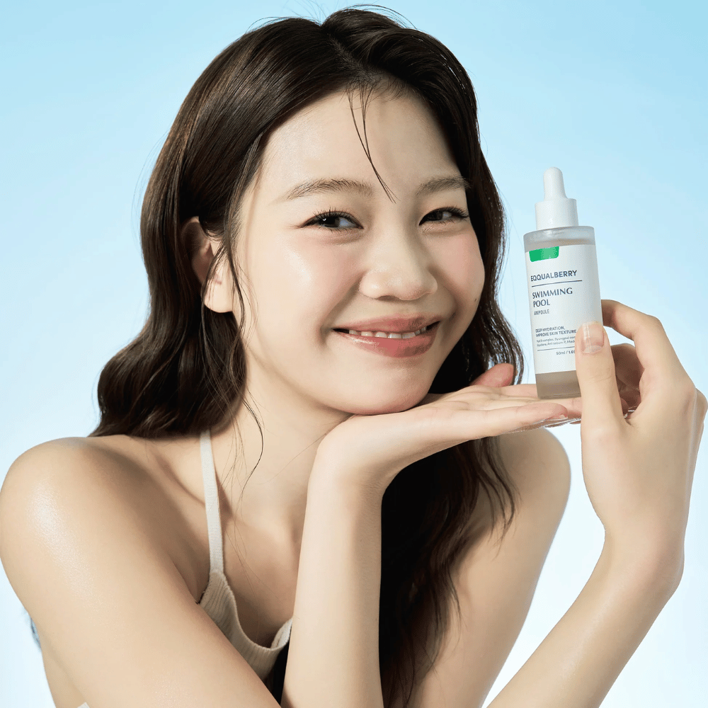 Lachende vrouw die Eqqualberry Swimming Pool Ampoule omhoog houdt, een hydraterend huidverzorgingsproduct, met beide handen voor een lichtblauwe achtergrond.