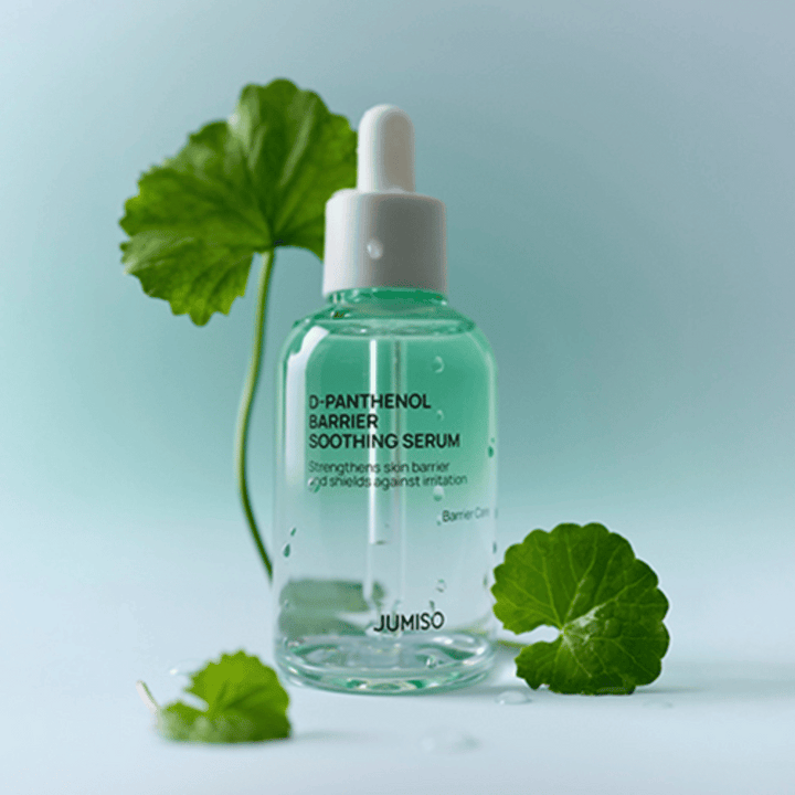 Jumiso D-Panthenol Barrier Soothing Serum i genomskinlig glasflaska med pipett, placerad med gröna blad i bakgrunden.