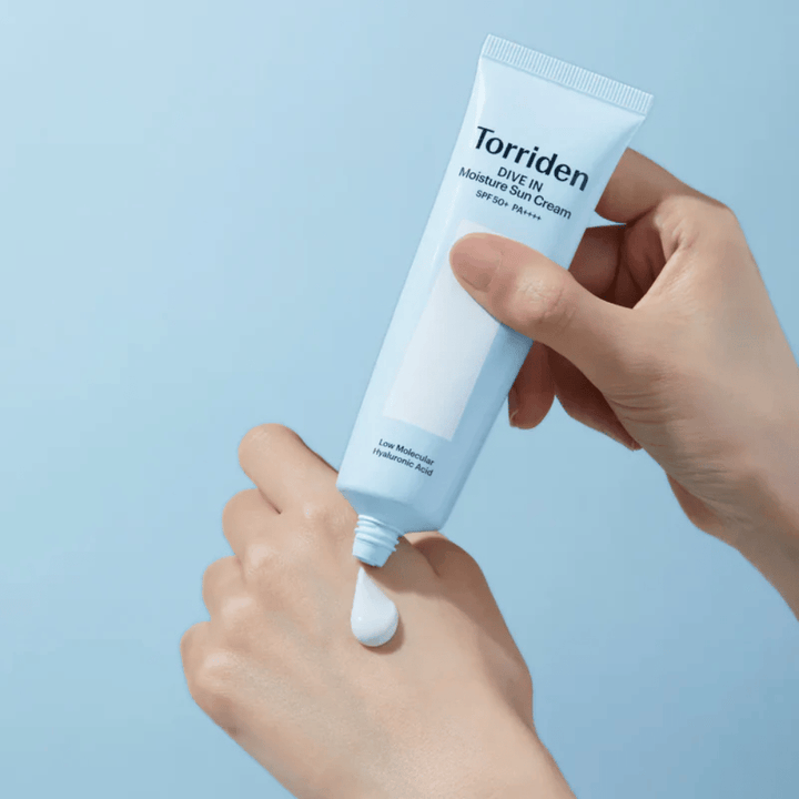 Torriden DIVE-IN Moisture Sun Cream SPF50+ PA++++ wordt op de hand aangebracht om de lichte en romige textuur van de hydraterende zonnecrème te tonen.