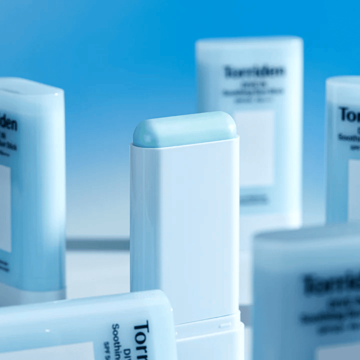 Close-up van Torriden DIVE IN Soothing Sun Stick die de zachte zonnebeschermingsformule in stickvorm toont, met meerdere producten op de achtergrond.