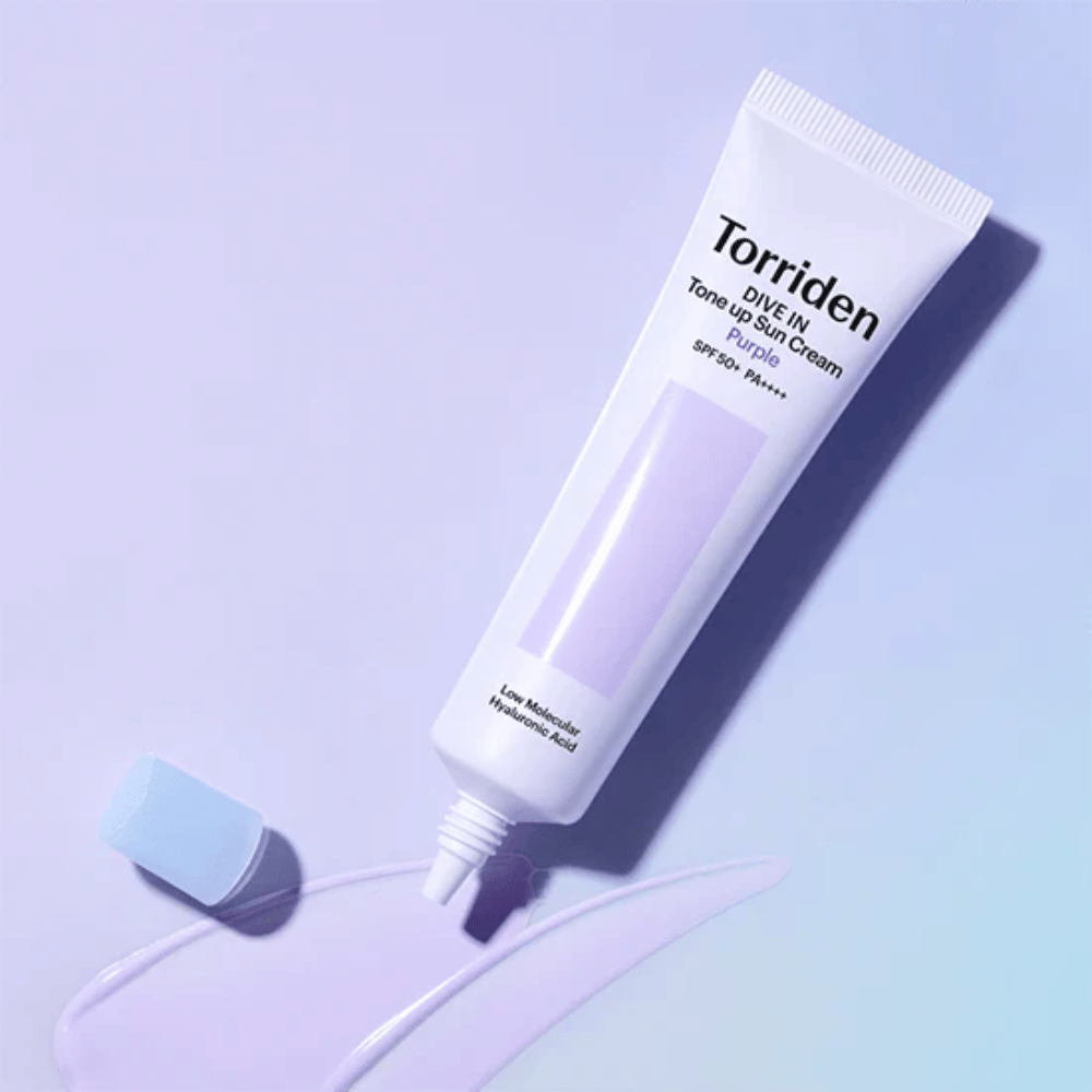 Geopende tube van Torriden DIVE IN Tone Up Sun Cream Purple met paars getinte zonnecrèmetextuur die de kleurcorrigerende formule van het product toont.
