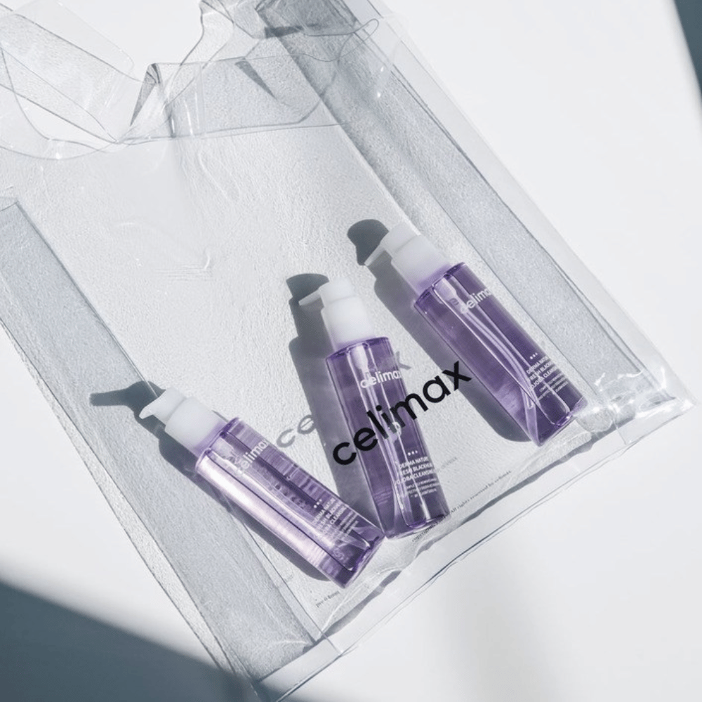 Drie flessen van Celimax Derma Nature Fresh Blackhead Jojoba Cleansing Oil in paarse verpakking, geplaatst in een transparante zak met het logo 'celimax'.
