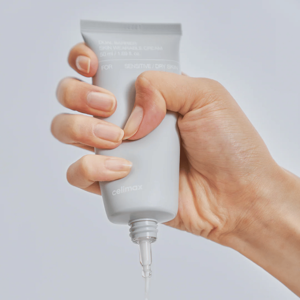 Hand die Celimax Dual Barrier Skin Wearable Cream aanbrengt, barrièreversterkende gezichtscrème voor gevoelige en droge huid die langdurige hydratatie biedt en de huidbarrière beschermt.