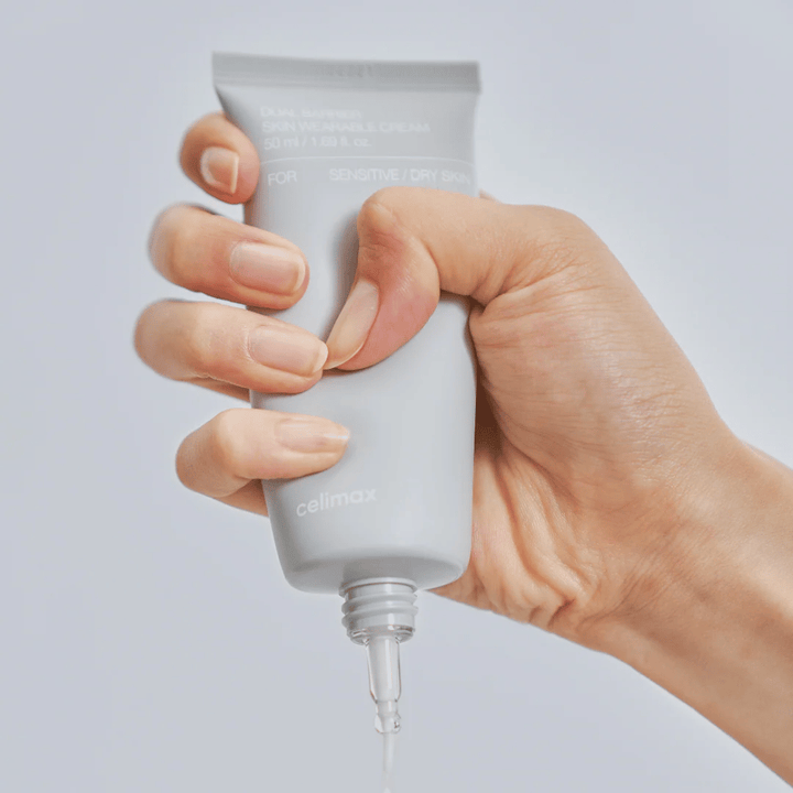 Hand die Celimax Dual Barrier Skin Wearable Cream aanbrengt, barrièreversterkende gezichtscrème voor gevoelige en droge huid die langdurige hydratatie biedt en de huidbarrière beschermt.