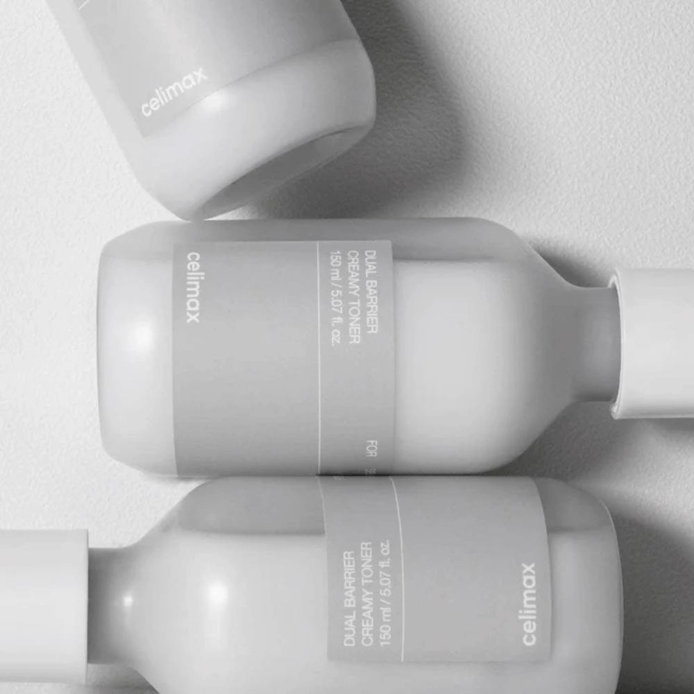 Drie liggende flessen van Celimax Dual Barrier Creamy Toner in een minimalistisch ontwerp met grijs etiket en zacht licht – perfect voor gevoelige en droge huid.
