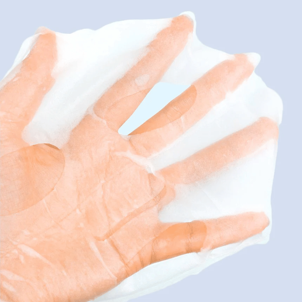 Een doorzichtige en vochtige gezichtsmasker wordt op een hand gehouden tegen een lichtblauwe achtergrond. Het masker is ontworpen om het gezicht te bedekken met openingen voor ogen en mond.