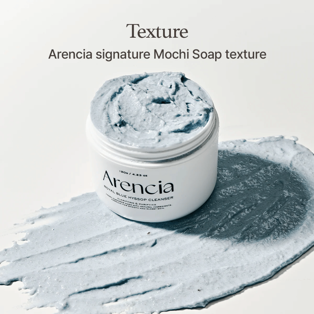 Open pot met Arencia Fresh Blue Hyssop Rice Mochi Cleanser, geplaatst bovenop een uitgesmeerde laag van de blauwe, romige reinigingsformule die de mochi-achtige textuur laat zien.