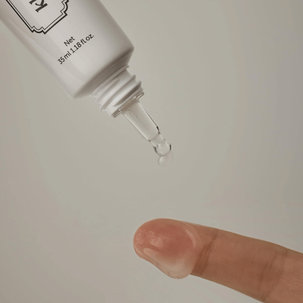 Detailbeeld waarop een heldere, lichte gel vanuit de smalle punt op een vinger wordt aangebracht. De afbeelding illustreert de transparante, gelachtige textuur van het product en de nauwkeurige applicatie rond de oogzone.
