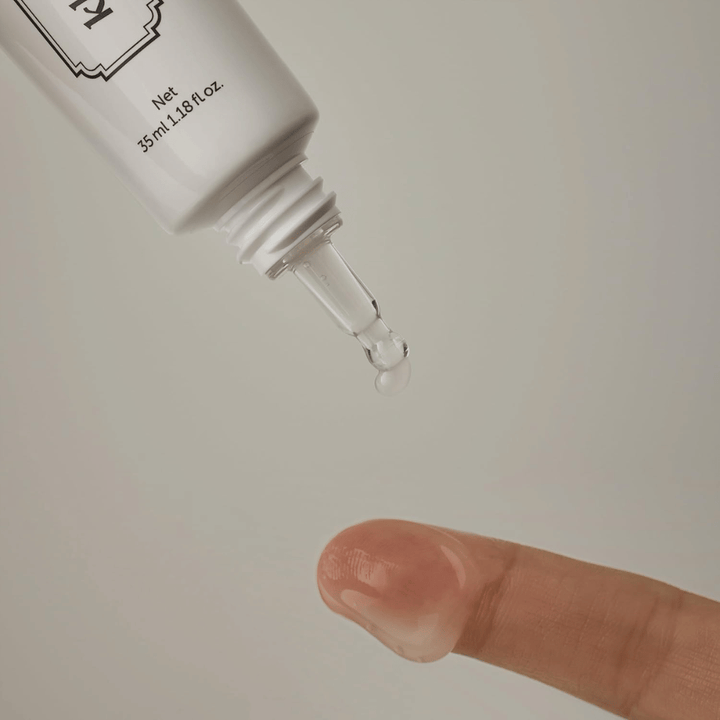 Detailbeeld waarop een heldere, lichte gel vanuit de smalle punt op een vinger wordt aangebracht. De afbeelding illustreert de transparante, gelachtige textuur van het product en de nauwkeurige applicatie rond de oogzone.