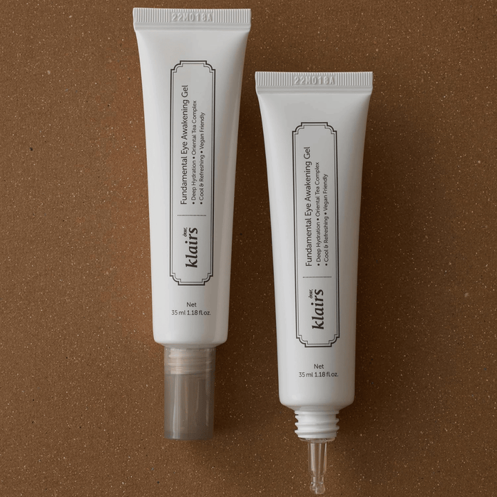 Productafbeelding die Klairs Fundamental Eye Awakening Gel in twee uitvoeringen toont – een gesloten tube en een open tube die de smalle applicatorpunt benadrukt. De verpakking heeft een minimalistisch wit ontwerp en legt de nadruk op de focus van het product op hydratatie, een verkoelend gevoel en verfrissende verzorging voor de oogzone.