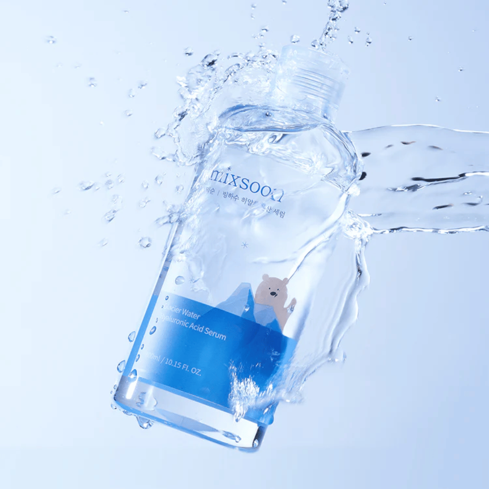 Mixsoon Glacier Water Hyaluronic Acid Serum-fles met blauw etiket en ijsberenmotief omgeven door spetterend water tegen een lichtblauwe achtergrond.