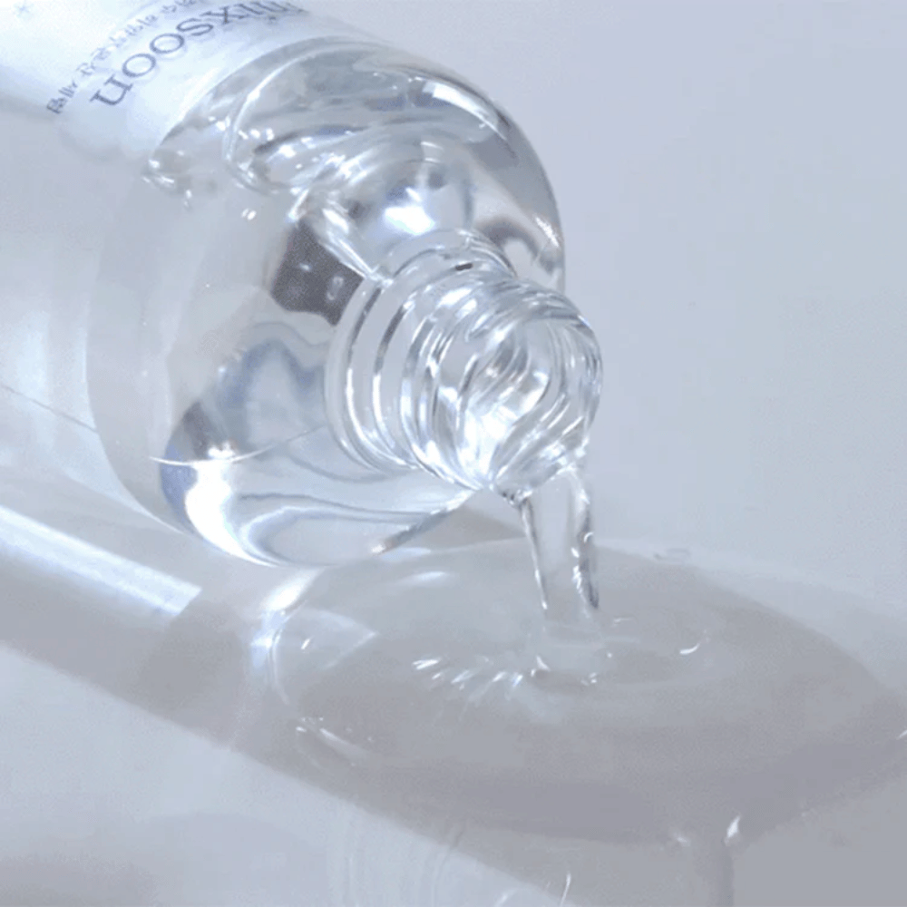 Close-up van doorzichtig serum dat uit een fles wordt gegoten Mixsoon Glacier Water Hyaluronic Acid Serum op een glanzend oppervlak.