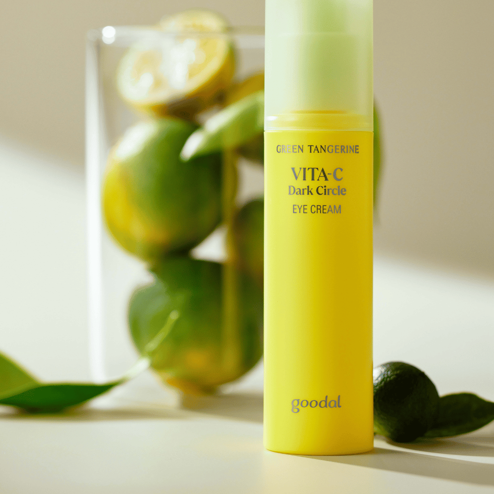 Een fles Goodal Green Tangerine Vita C Dark Circle Eye Cream 30ml op een tafel naast een limoen.
